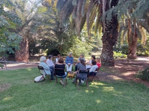 Participantes seniors reunidos bajo palmeras en círculo de diálogo